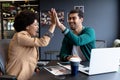 Happy diverse businessman and businesswoman high fiving in creative office