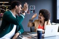 Happy diverse businessman and businesswoman high fiving in creative office