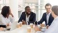 Happy diverse businesspeople talk at negotiations sit at office table