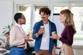 Diverse colleagues have fun at lunch break in office, smiling multiracial employees laugh and talk drinking coffee Royalty Free Stock Photo