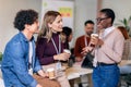 Diverse colleagues have fun at lunch break in office, smiling multiracial employees laugh and talk drinking coffee Royalty Free Stock Photo