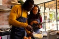 Happy diverse couple baking mixing dough and suing tablet in kitchen