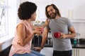 Happy diverse couple in kitchen drinking coffee and smiling Royalty Free Stock Photo