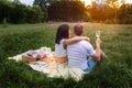Happy diverse couple relaxing on blanket, having picnic in sunny garden, holding wine glass. Royalty Free Stock Photo
