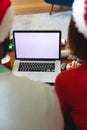 Happy diverse couple wearing santa claus hats, using laptop with copy space Royalty Free Stock Photo