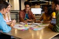 Happy diverse creative colleagues in discussion brainstorming using tablet and notes in office Royalty Free Stock Photo