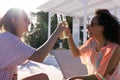 Happy diverse female friends having party by swimming pool, sitting on deck chairs and making toast Royalty Free Stock Photo