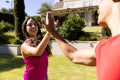 Happy diverse fit couple practicing yoga high fiving and smiling in sunny garden Royalty Free Stock Photo