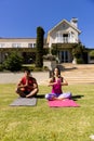 Happy diverse fit couple practicing yoga meditation sitting in sunny garden, with copy space Royalty Free Stock Photo