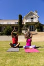 Happy diverse fit couple practicing yoga meditation sitting in sunny garden, with copy space Royalty Free Stock Photo