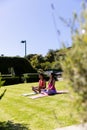 Happy diverse fit couple practicing yoga meditation sitting in sunny garden, with copy space Royalty Free Stock Photo