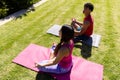 Happy diverse fit couple practicing yoga meditation sitting in sunny garden Royalty Free Stock Photo