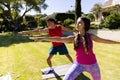 Happy diverse fit couple practicing yoga standing and stretching in sunny garden Royalty Free Stock Photo