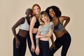 Happy multicultural models wearing sportswear standing at beige background. Royalty Free Stock Photo