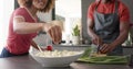 Happy diverse friends preapring meal in kitchen, slow motion