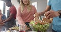 Happy diverse group of friends preapring meal in kitchen, slow motion