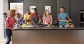 Happy diverse group of friends preapring meal in kitchen, slow motion