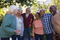 Happy diverse group of senior friends embracing and laughing in sunny garden Royalty Free Stock Photo