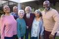 Happy diverse group of senior friends embracing next to house in sunny garden Royalty Free Stock Photo