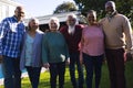 Happy diverse group of senior friends embracing next to pool in sunny garden Royalty Free Stock Photo