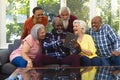 Happy diverse group of senior friends using tablet and laughing in sunny living room Royalty Free Stock Photo