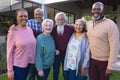 Happy diverse group of senior friends walking next to house in sunny garden Royalty Free Stock Photo