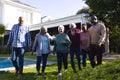 Happy diverse group of senior friends walking next to pool in sunny garden Royalty Free Stock Photo