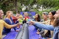 Happy diverse large group of multicultural friends making celebratory toast holding beautiful gourmet cocktail glasses sitting at Royalty Free Stock Photo