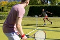 Happy diverse male friends playing tennis together at tennis court Royalty Free Stock Photo