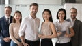 Happy diverse professional leaders looking at camera stand with employees