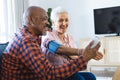 Happy diverse senior man testing blood pressure of senior woman in sunny living room Royalty Free Stock Photo