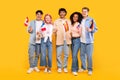 Happy diverse students of language school, teens of different nationalities holding little flags, yellow background Royalty Free Stock Photo