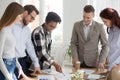 Happy diverse team brainstorm in office with papers on table Royalty Free Stock Photo