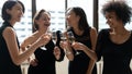 Happy diverse women wearing elegant black dresses clinking champagne glasses