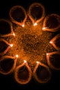 Happy Diwali and circle of Diya - many Terracotta diyas or oil lamps arranged over clay surface or ground in round or circular sha