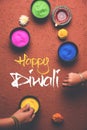 Happy Diwali Greeting card using colourful Rangoli in bowls, diya or clay lamp and happy diwali writing with flowers