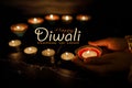 Happy Diwali - Woman hands with henna holding lit candle isolated on dark background Royalty Free Stock Photo