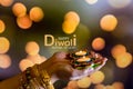 Happy Diwali - Woman hands with henna holding lit candle isolated on dark background. Clay Diya lamps lit during Dipavali, Hindu Royalty Free Stock Photo