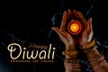 Happy Diwali - Woman hands with henna holding lit candle isolated on dark background Royalty Free Stock Photo