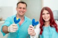 Happy doctor dentist with his patient show the result of impressions of her teeth on a spoon with silicone material