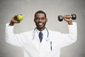 Happy doctor holding green apple, dumbbell Royalty Free Stock Photo