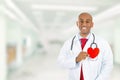 Happy doctor holding red heart standing in hospital hallway