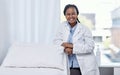 Happy doctor leaning on a hospital bed smiling, standing and ready to serve, assist and help you get healthy. Cheerful