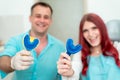 Happy doctor orthodontist with his patient demonstrate the result of impressions of her teeth on a spoon with silicone material