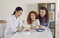 Happy doctor, parent and little kid looking at anatomical spine model and laughing