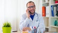 Happy doctor phoning in his modern office. Royalty Free Stock Photo