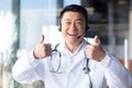 Happy doctor smiles and looks at the camera, Asian announces good news to the patient, uses a video call, and a headset online