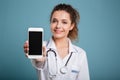 Happy doctor with stethoscope showing blank smartphone screen Royalty Free Stock Photo