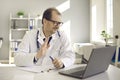 Happy doctor waving hello at laptop greeting patient in online video consultation Royalty Free Stock Photo
