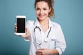 Happy doctor in white coat showing blank smartphone screen Royalty Free Stock Photo